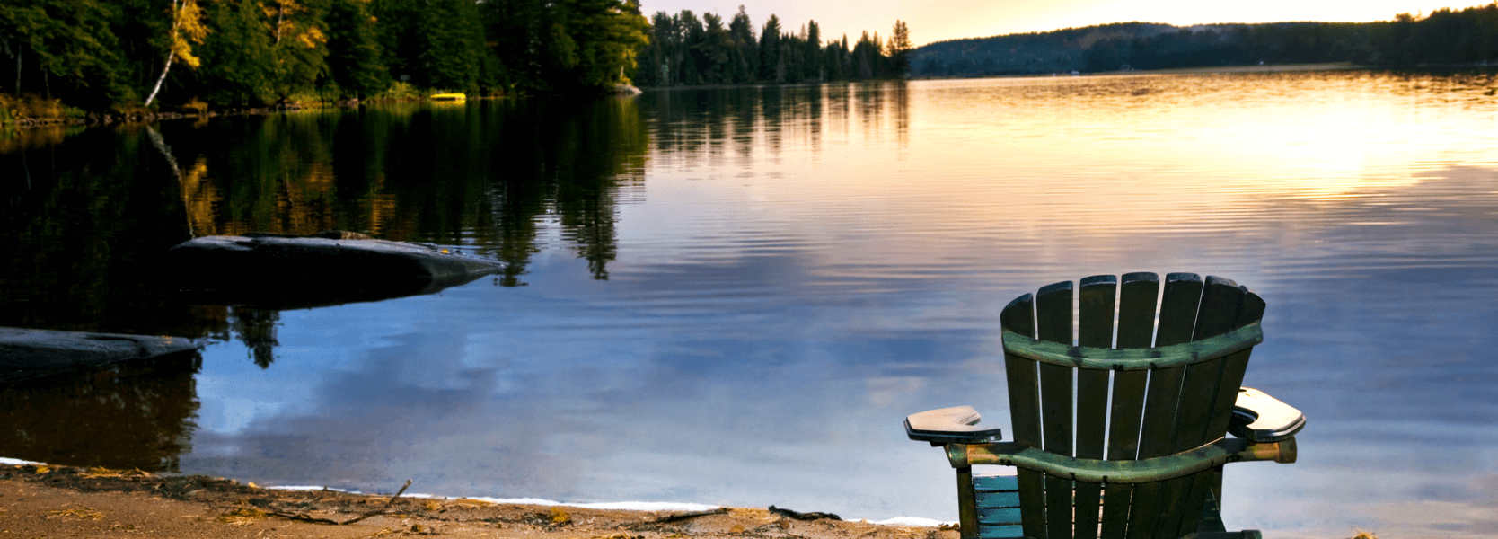 An empty Adirondack chair overlooking a serene lake in Muskoka, Ontario.